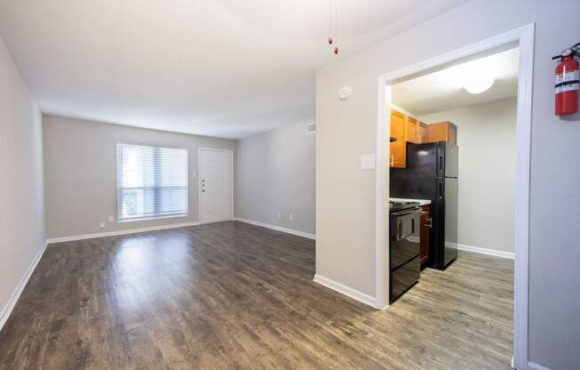 A room with a wooden floor and a black fridge.