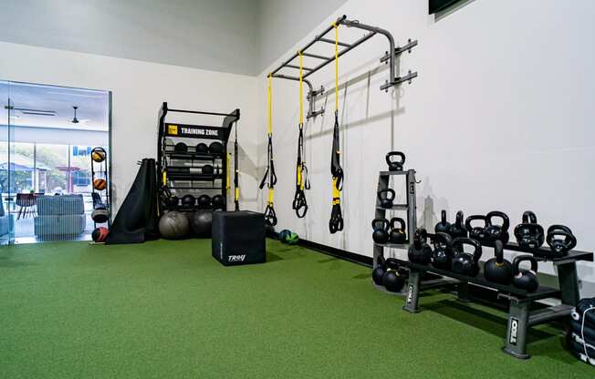a gym with green carpet and weights on the wall