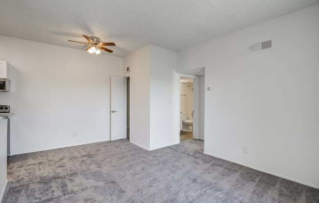 an empty living room with white walls and a ceiling fan