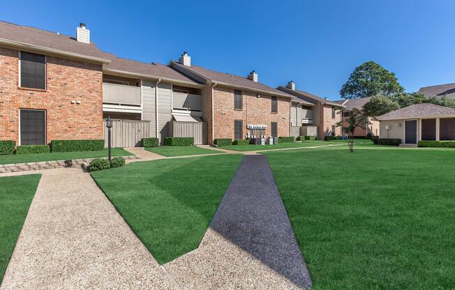 a large brick building with green grass in front of a house