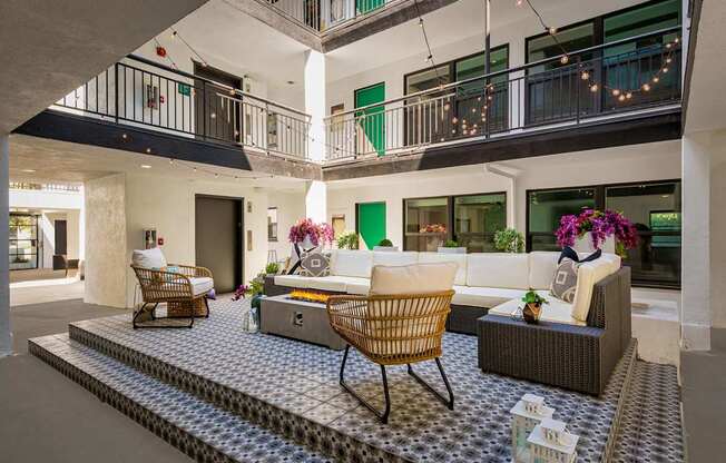 A patio with a table and chairs is surrounded by a balcony.