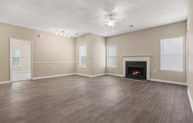 an empty living room with a fireplace and a ceiling fan