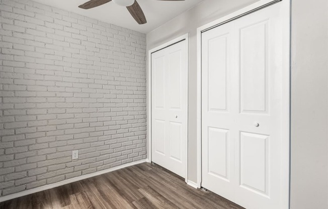 an empty room with white doors and a ceiling fan at Town & Country Apartments - Wixom, MI, Michigan