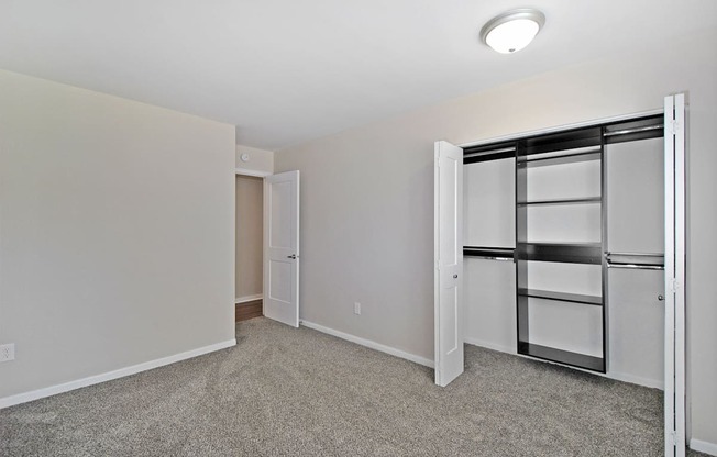 a bedroom with white walls and a closet with a mirrored door