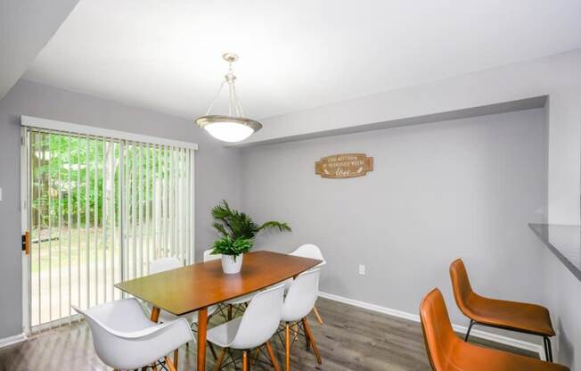 A dining room with a wooden table and white chairs.