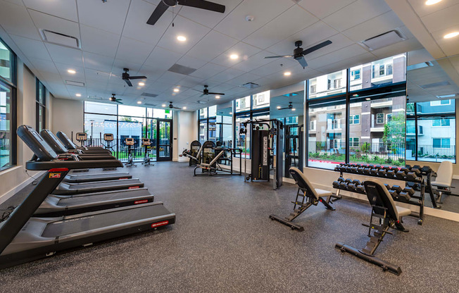 a gym with treadmills and other exercise equipment in a building with windows