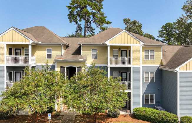 A row of houses with balconies and trees in front.