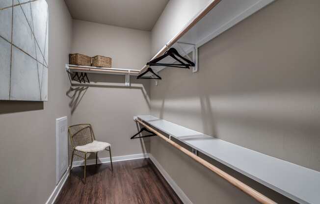 a spacious walk in closet in a bedroom with a desk and a chair