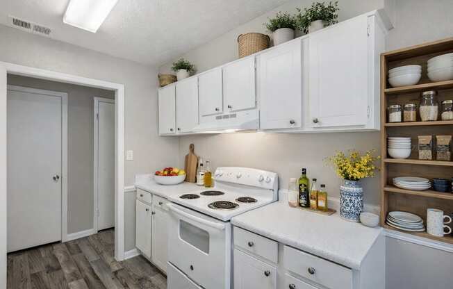 A kitchen with white cabinets and a white stove top oven.