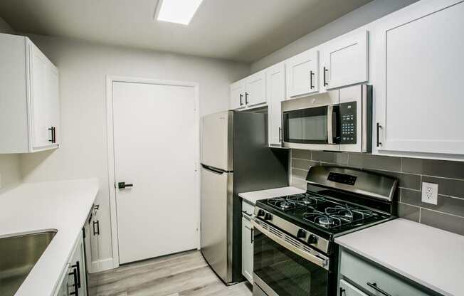 a kitchen with white cabinets and stainless steel appliances