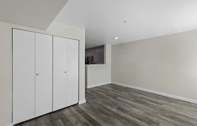 Living Area with a medium sized white Coat Closet and Small View of Kitchen in the Background at Excalibur Apartment Homes, Bellevue, WA