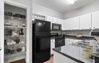 a kitchen with black appliances and white cabinets and granite counter tops