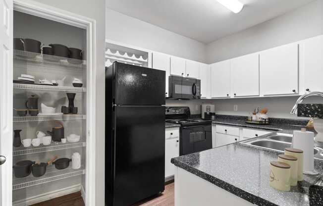 a kitchen with black appliances and white cabinets and granite counter tops