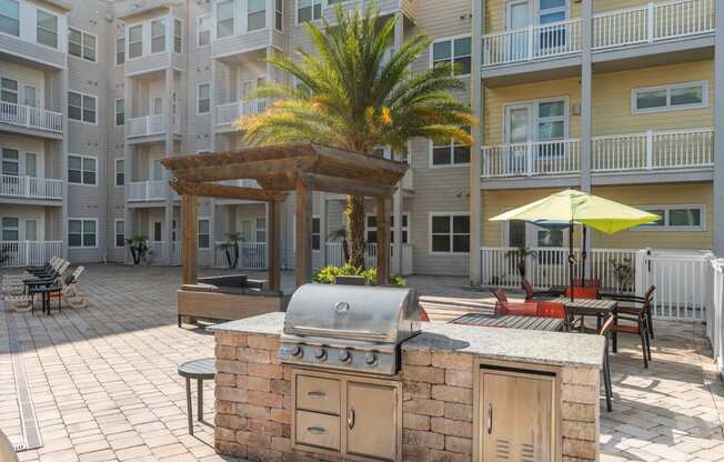 a large outdoor kitchen with a grill in front of an apartment building