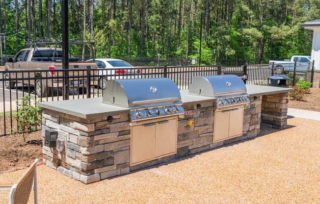 an outdoor kitchen with two grills next to a fence at Preston Ridge, Cary