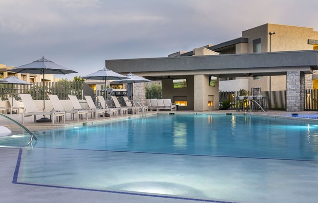 a resort style pool with lounge chairs and umbrellas