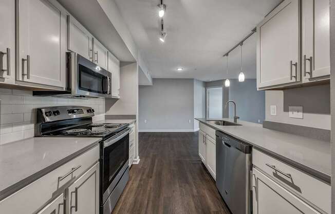 A kitchen with white cabinets and dark wood floors.