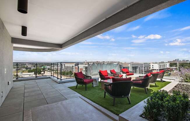 A patio with red chairs and a glass table.