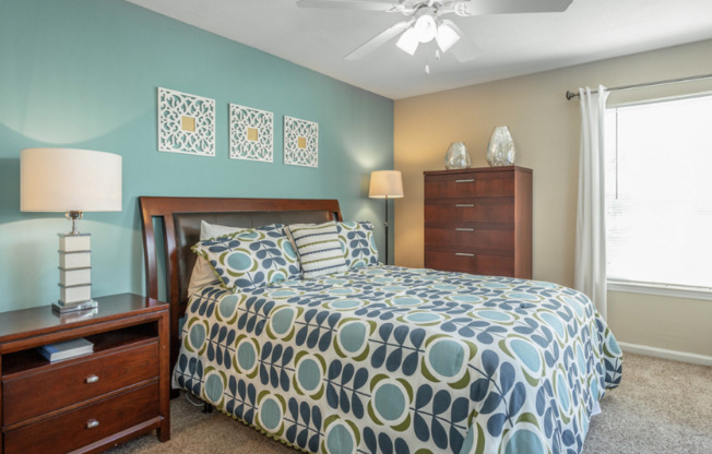 Spacious bedroom with plush carpeting, ceiling fan, and large windows at Preakness Apartments