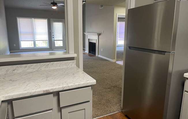 A kitchen with a marble counter top and a stainless steel refrigerator.