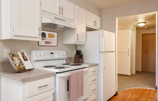 A kitchen with white cabinets and appliances.