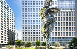 a sculpture in a park in front of a tall building