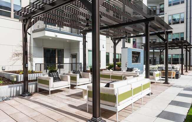 A patio with white couches and a black pergola.