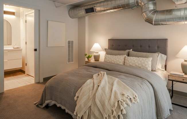 a bedroom with a bed and a exposed duct in the ceiling at The 22 Apartments, St. Louis, MO 63103