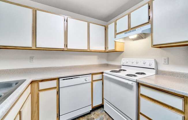 an empty kitchen with white appliances and wooden cabinets