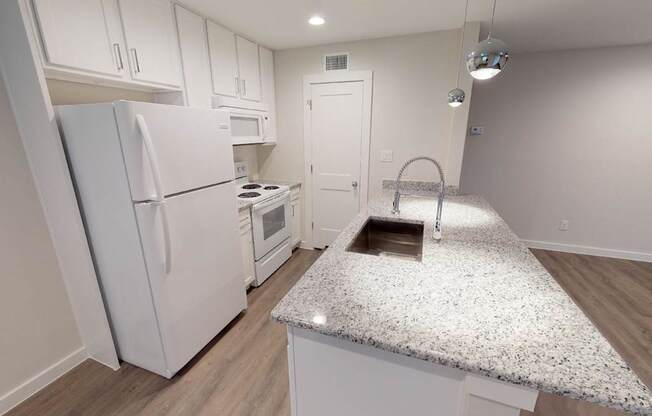 A kitchen with white cabinets and a granite countertop.