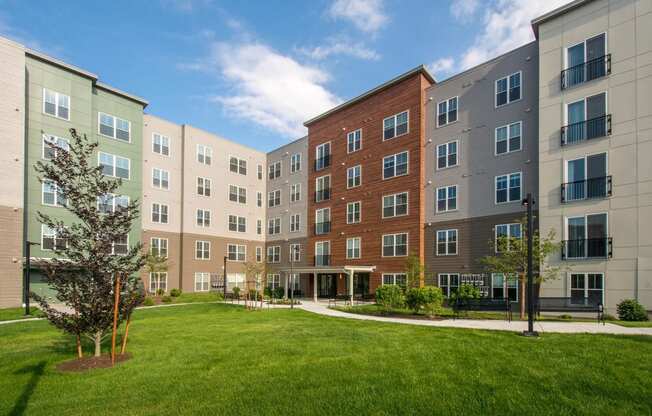 an exterior view of an apartment building with a green lawn