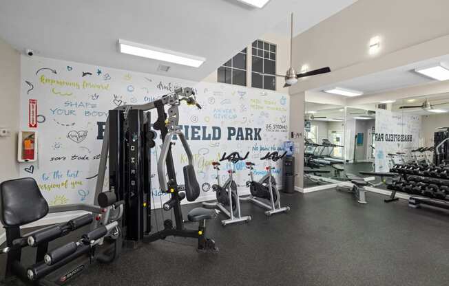 a gym with weights and a white wall with writing on it