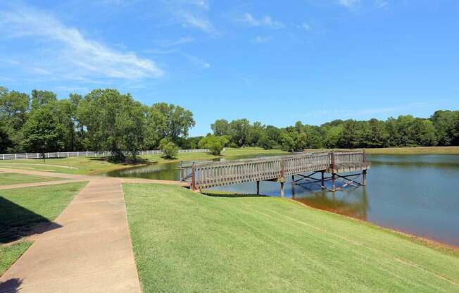 A wooden bridge over a body of water with a grassy area on the left.