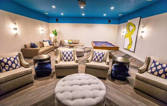 A room with a pool table and comfortable seating.
