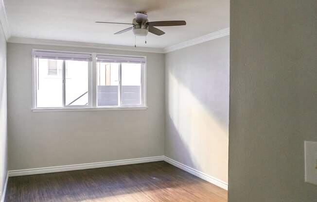 an empty room with a ceiling fan and a window