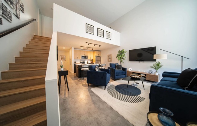 a living room with couches and chairs and a staircase