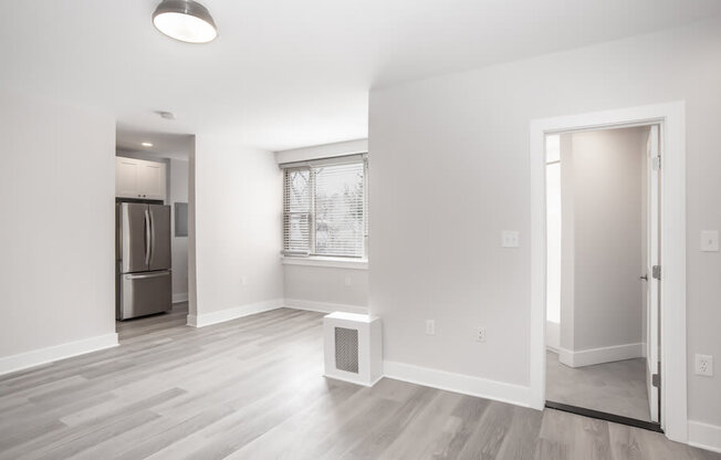 empty living room with a large window and a door to a kitchen