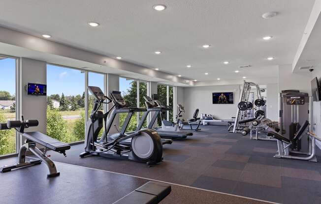 a gym with treadmills and other exercise equipment and windows