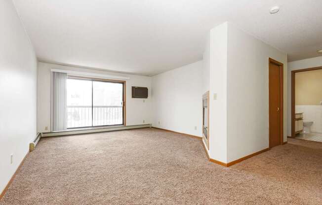 an empty living room with a window and a door to a bathroom. Anoka, MN Dellwood Estates