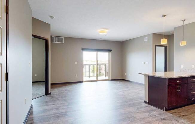 A spacious living area with neutral walls and wood-style flooring.