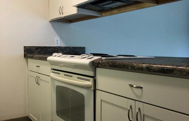 a kitchen with white cabinets and a white stove top oven