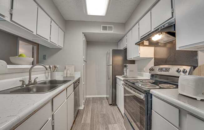 A kitchen with white cabinets and a stove top oven.