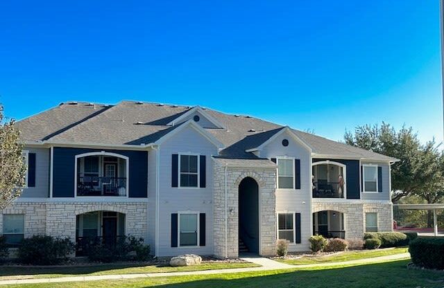 a large white house with a yard and a blue sky
