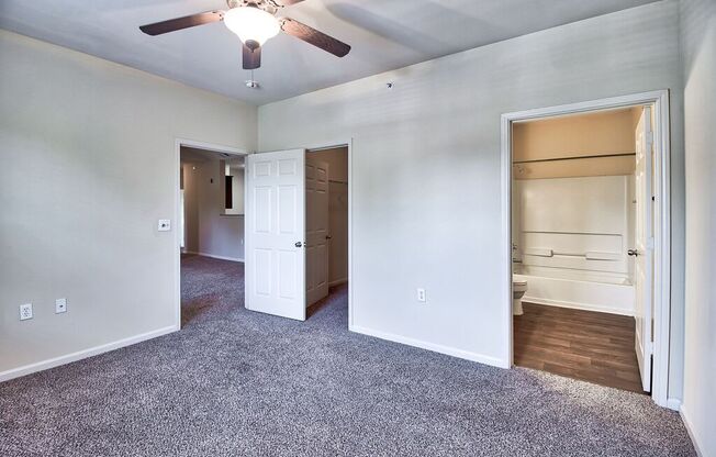an empty living room with a ceiling fan and a closet