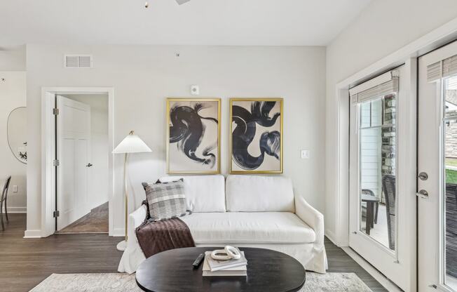 a living room with a white couch and two paintings on the wall