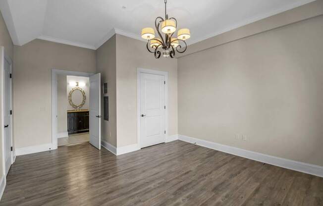 an empty living room with wood floors and a chandelier at The Knights @ 506 Delaware Apartments, Buffalo, 14202