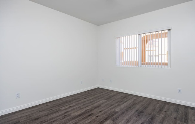 a bedroom with white walls and a window