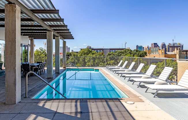 A pool surrounded by sun loungers and a metal roof.