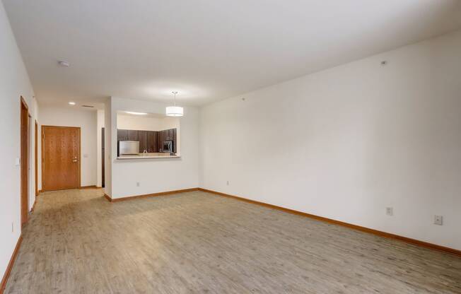 an empty living room with wood flooring and white walls