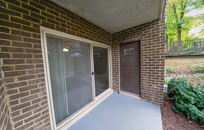 A patio area with a sliding glass door and a brick wall.